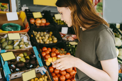 Side view of female customer buying fruits at market