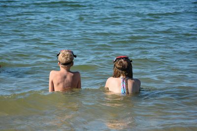 Rear view of two women swimming in sea