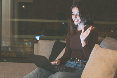 Portrait of young woman sitting on chair at night