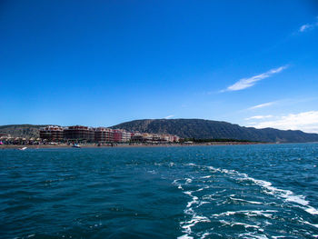 Scenic view of sea and mountains against blue sky