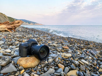 Pebbles on rocks by sea against sky