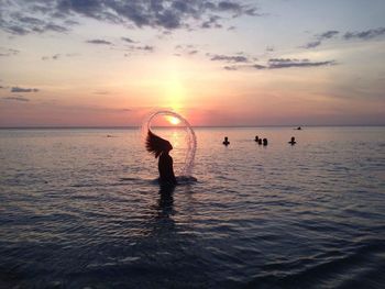 Side view of silhouette woman tossing hair in the sea