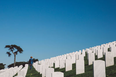 Rear view of woman walking amidst graves at cemetery