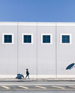 Side view of man walking on road against clear sky