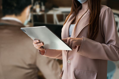 Midsection of woman using digital tablet