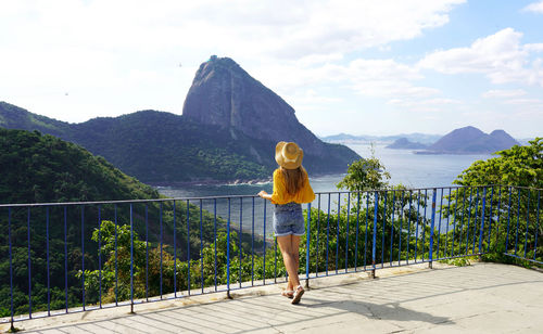 Traveler woman looking cable cars climb from urca hill to sugarloaf mountain, rio de janeiro, brazil