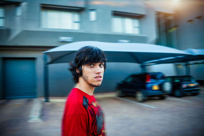 Portrait of young man looking away while standing on street