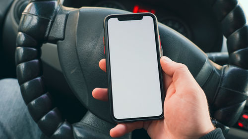 Close-up of hand using mobile phone in car