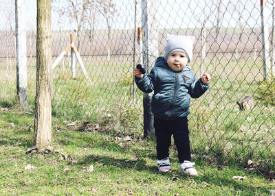 Full length of a boy playing with fence