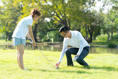 Full length of couple playing golf on field