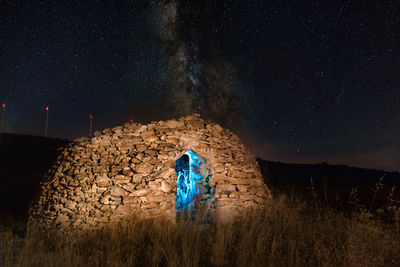 Old light painting on field against sky at night