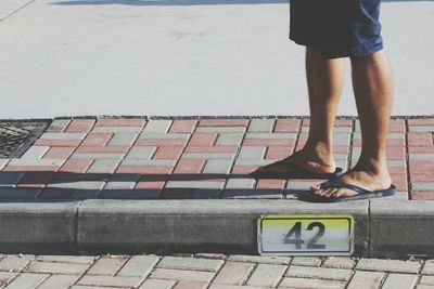 Low section of man standing by number on footpath