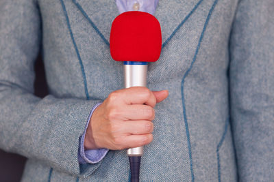 Midsection of man holding microphone