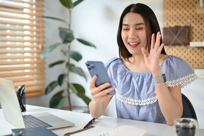 Portrait of young woman using mobile phone while sitting at home