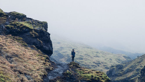 Man standing on cliff by sea against clear sky