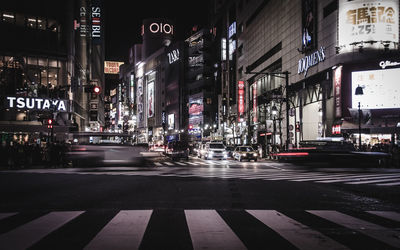 Vehicles on illuminated city street at night