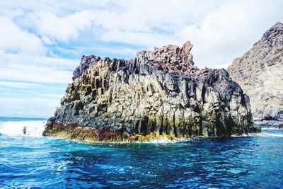 Rock formation in sea against sky