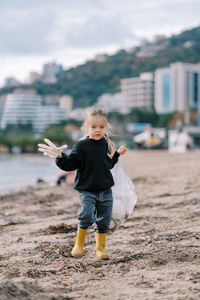 Side view of young woman standing on sand at beach