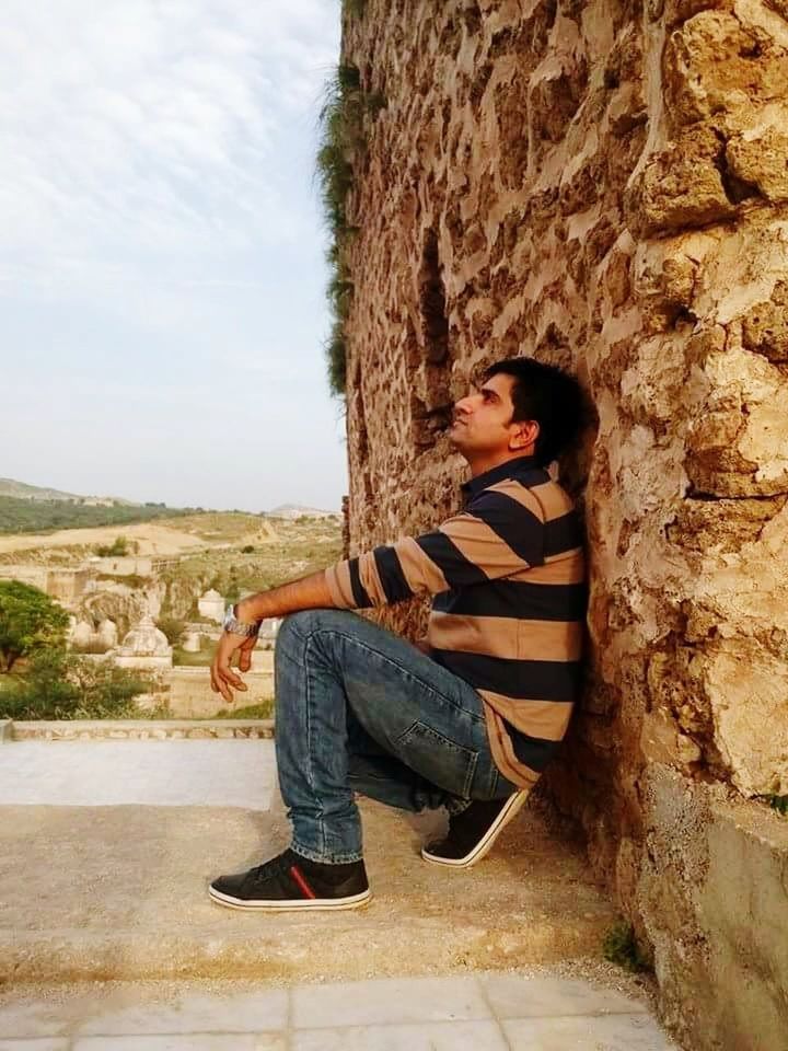 SIDE VIEW OF BOY SITTING AGAINST TREE