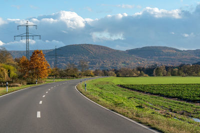 Road amidst field against sky