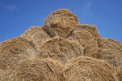 Low angle view of hay bales on field against sky