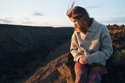 Woman during sunset looking down with hair blowing in wind