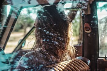 Woman sitting in car seen through window