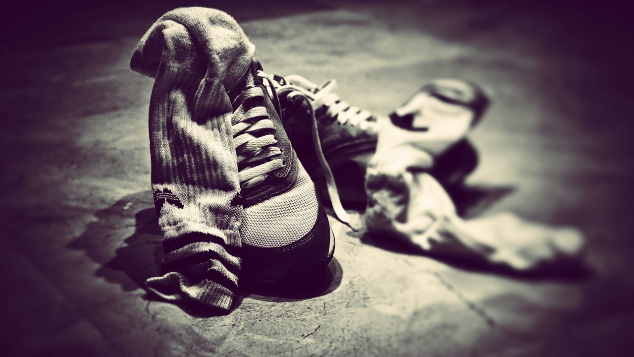 LOW SECTION OF MAN WEARING CANVAS SHOES ON FLOOR