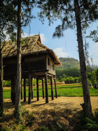 Built structure by trees on field against sky