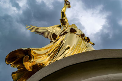 Low angle view of statue against sky and building