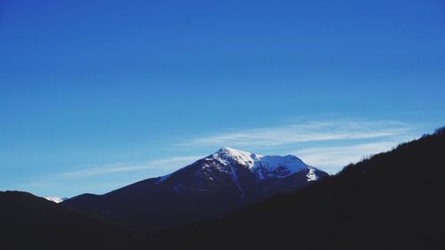 Scenic view of snowcapped mountains against blue sky