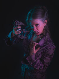 Portrait of spooky woman standing against black background