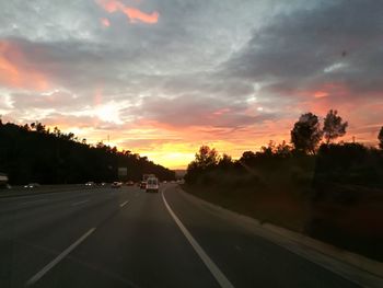 Cars on road against sky during sunset
