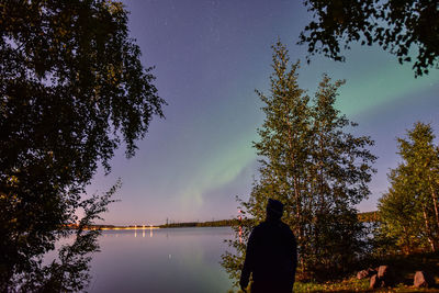 Silhouette man standing by lake against sky