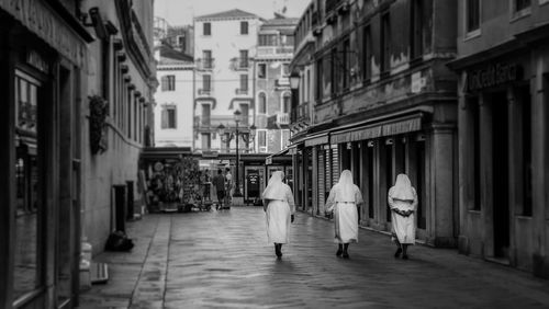 Rear view of nuns walking on road along buildings