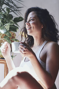 Smiling young woman looking away while holding drink