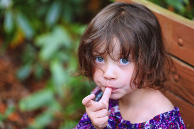 Portrait of cute girl sucking thumb outdoors