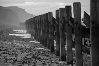 Wooden posts on beach against sky