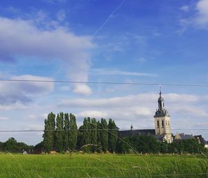 Windmill on field against cloudy sky