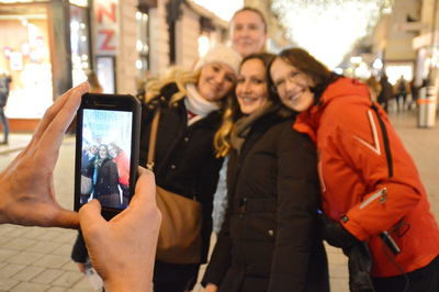 Portrait of young woman photographing in city