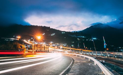 Light trails on road against sky at night