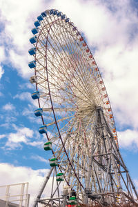 Low angle view of ferris wheel against cloudy sky