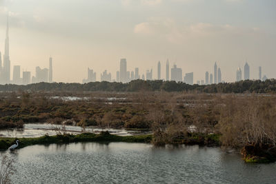 River by buildings in city against sky