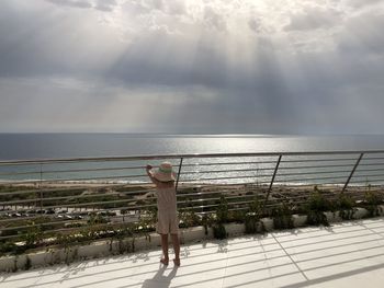 Woman by sea against sky