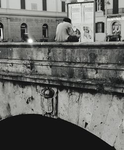 Woman with dog sitting in front of building