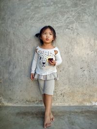 Portrait of young woman standing against wall