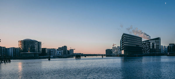 City by river against clear sky