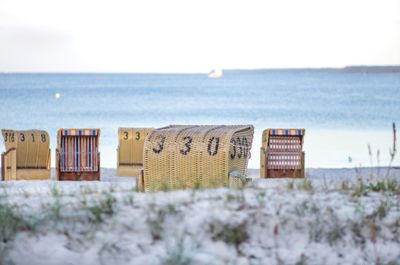 Hooded chairs on beach against sky