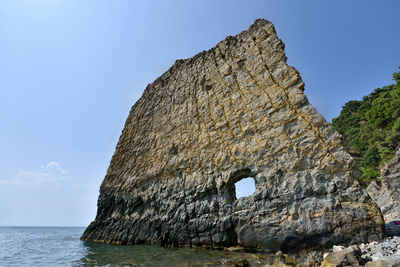 Rock formation in sea against clear blue sky