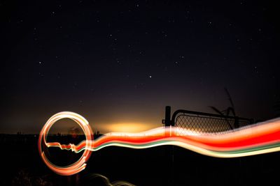 Low angle view of light trails against sky at night